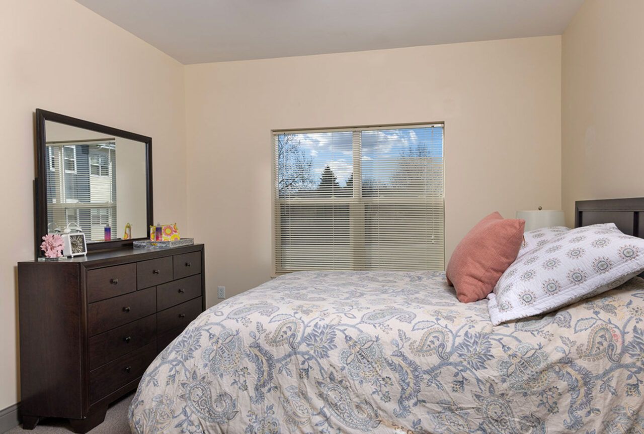 A well-decorated bedroom with a bed, dresser, and window.