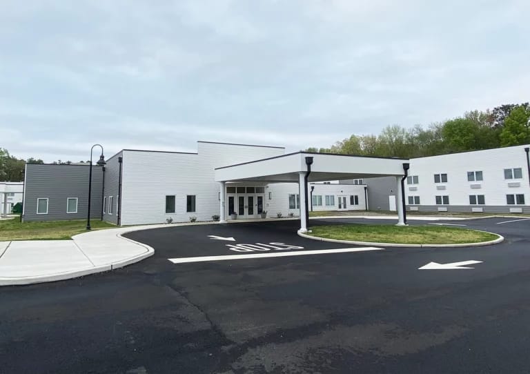 Exterior view of New Standard Living facility with parking area