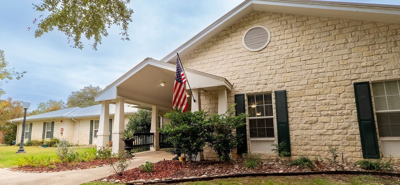 Entrance of the senior living facility with American flag