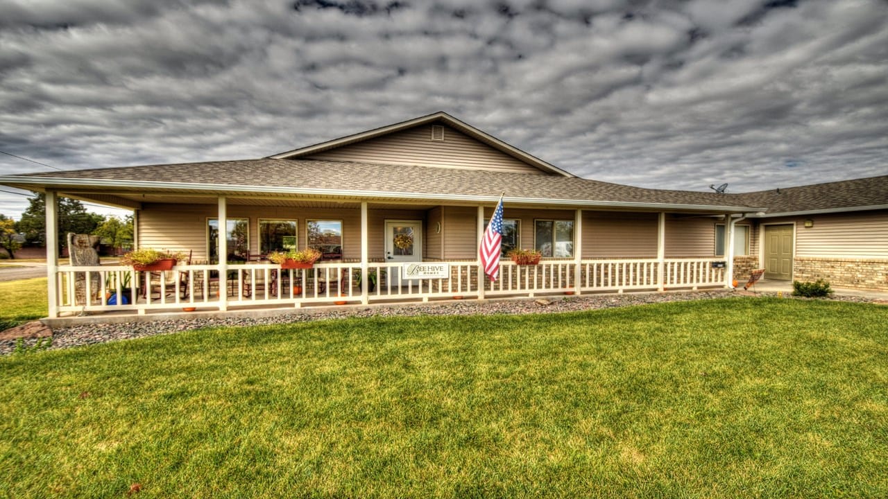 Exterior view of BeeHive Homes facility with garden and flag