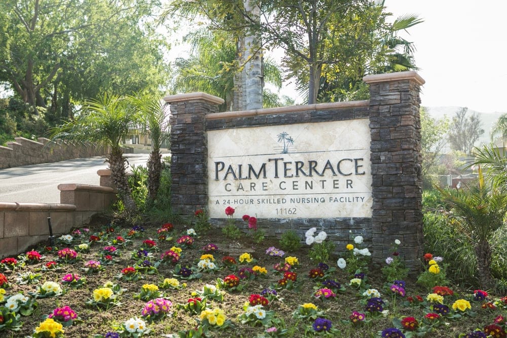 Exterior sign of Palm Terrace Care Center with flowers