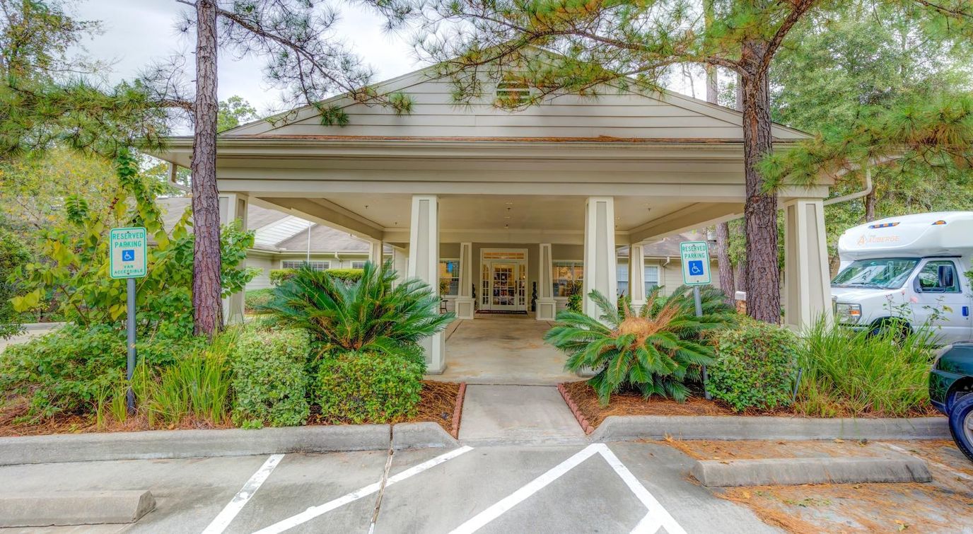 Front entrance of assisted living facility surrounded by greenery