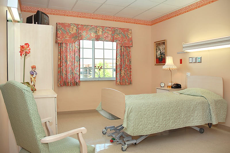 A well-furnished resident room with a bed and chair