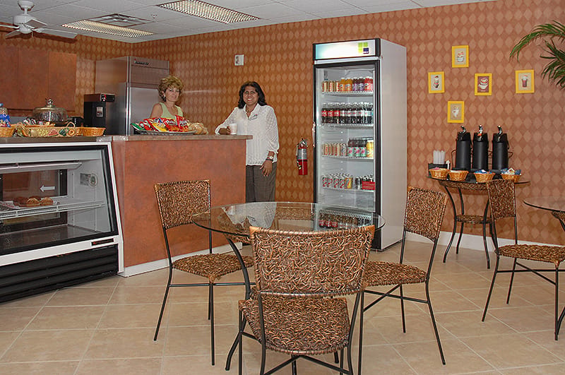 Two staff members in a common area with seating and refreshments