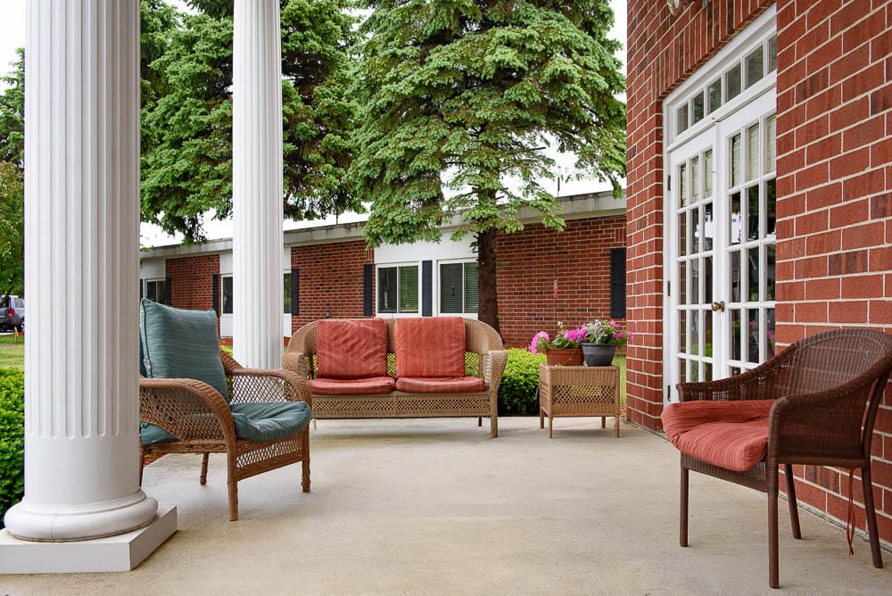 Covered outdoor seating area with chairs and plants