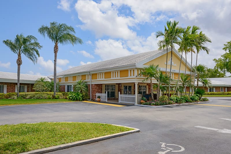 Exterior view of a nursing home facility with palm trees