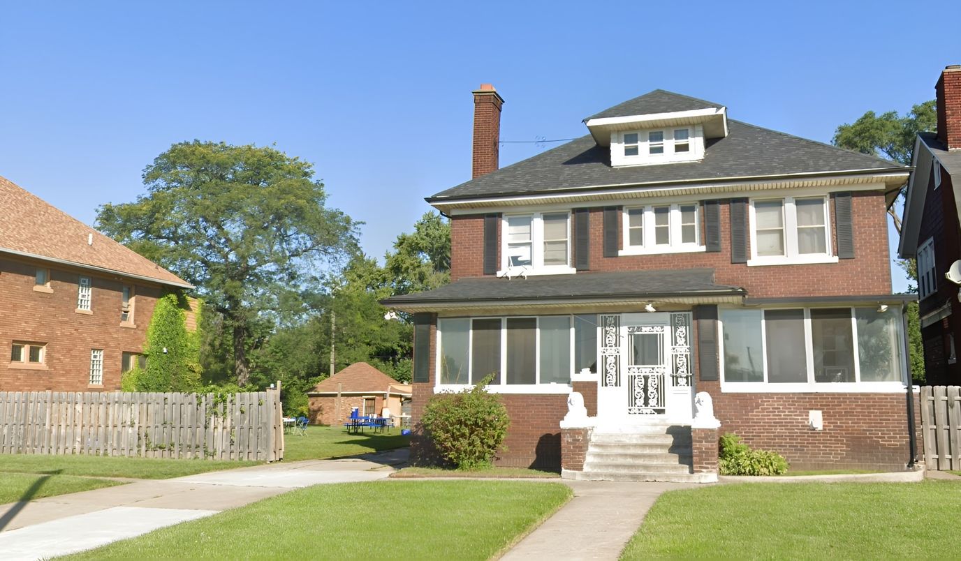 Exterior view of a residential building with grass and sidewalk