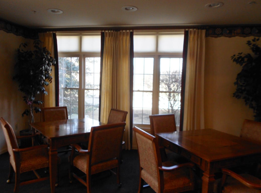 Cozy common area with tables and chairs by large windows