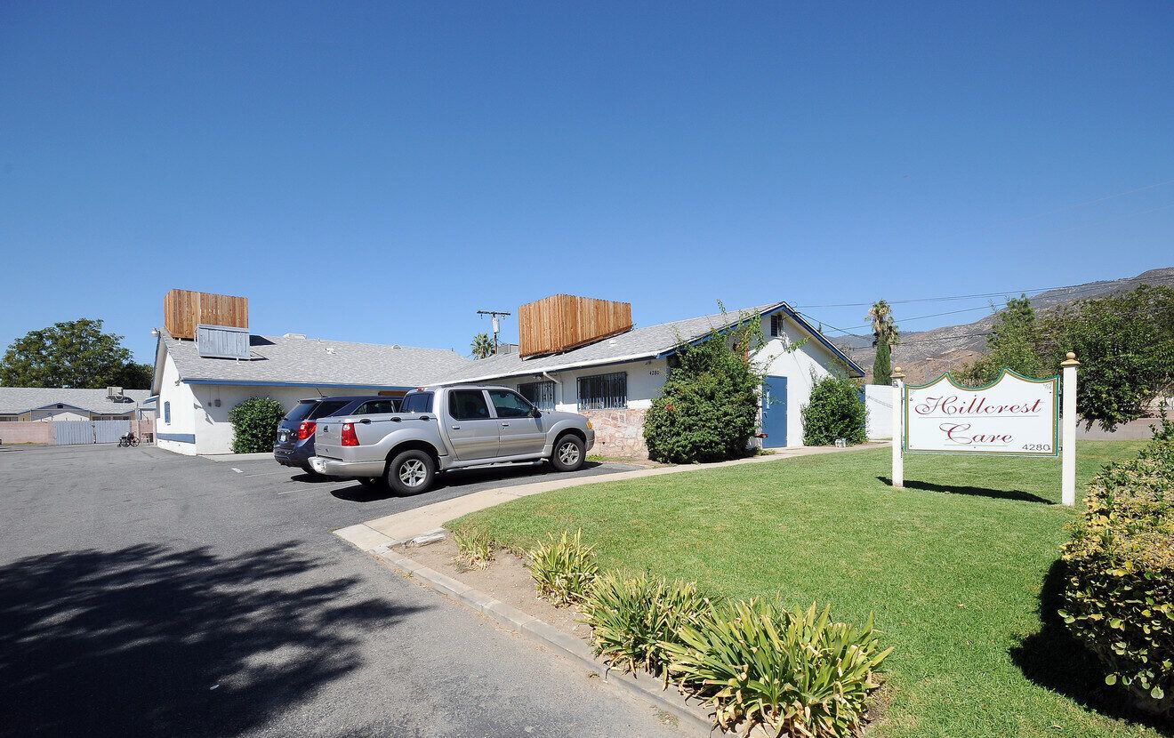 Exterior view of Hillcrest Care facility with cars in driveway