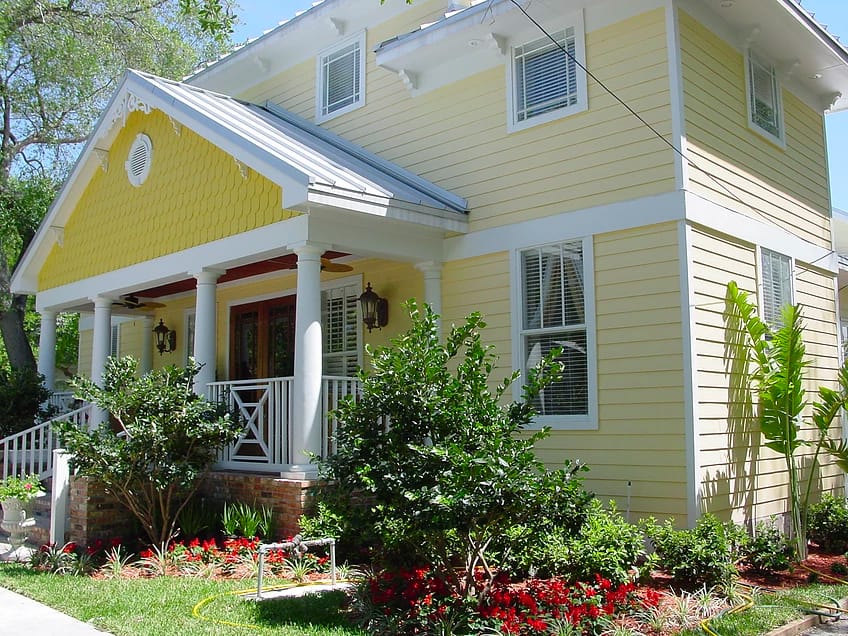 Exterior view of a yellow house with landscaped garden