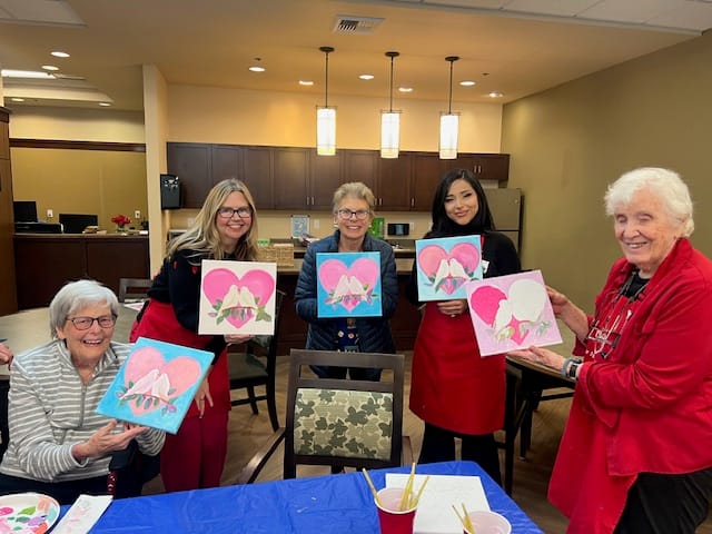 Residents and staff showing off their artwork in a common area