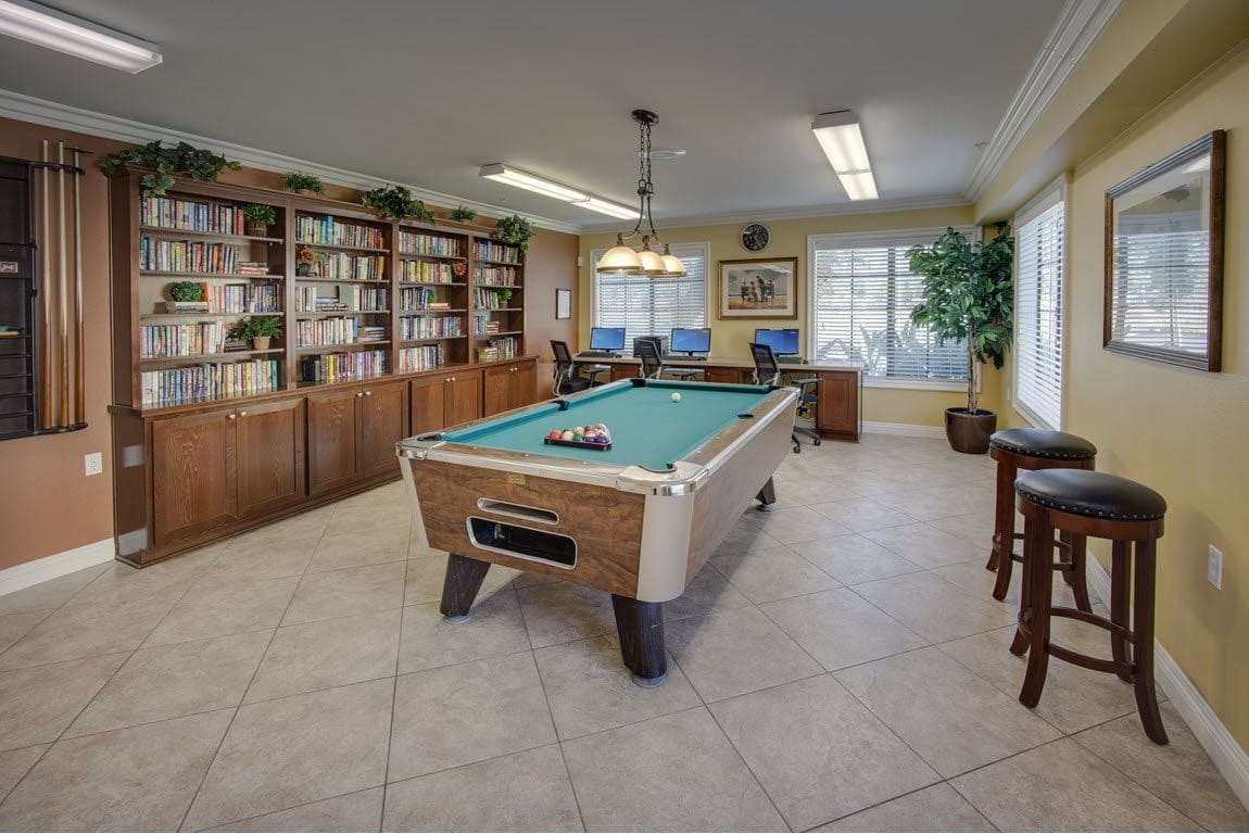 Billiards table in a communal room with bookshelves and computers.