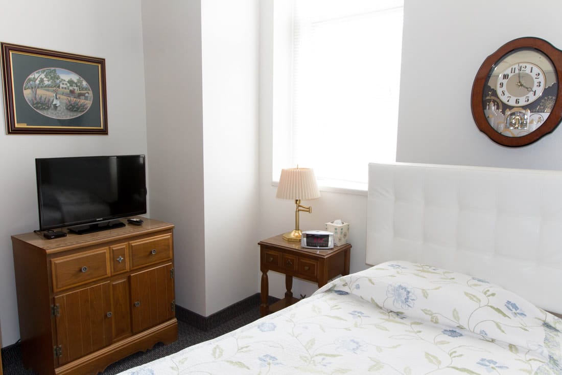 Cozy resident room with bed, TV, and furniture