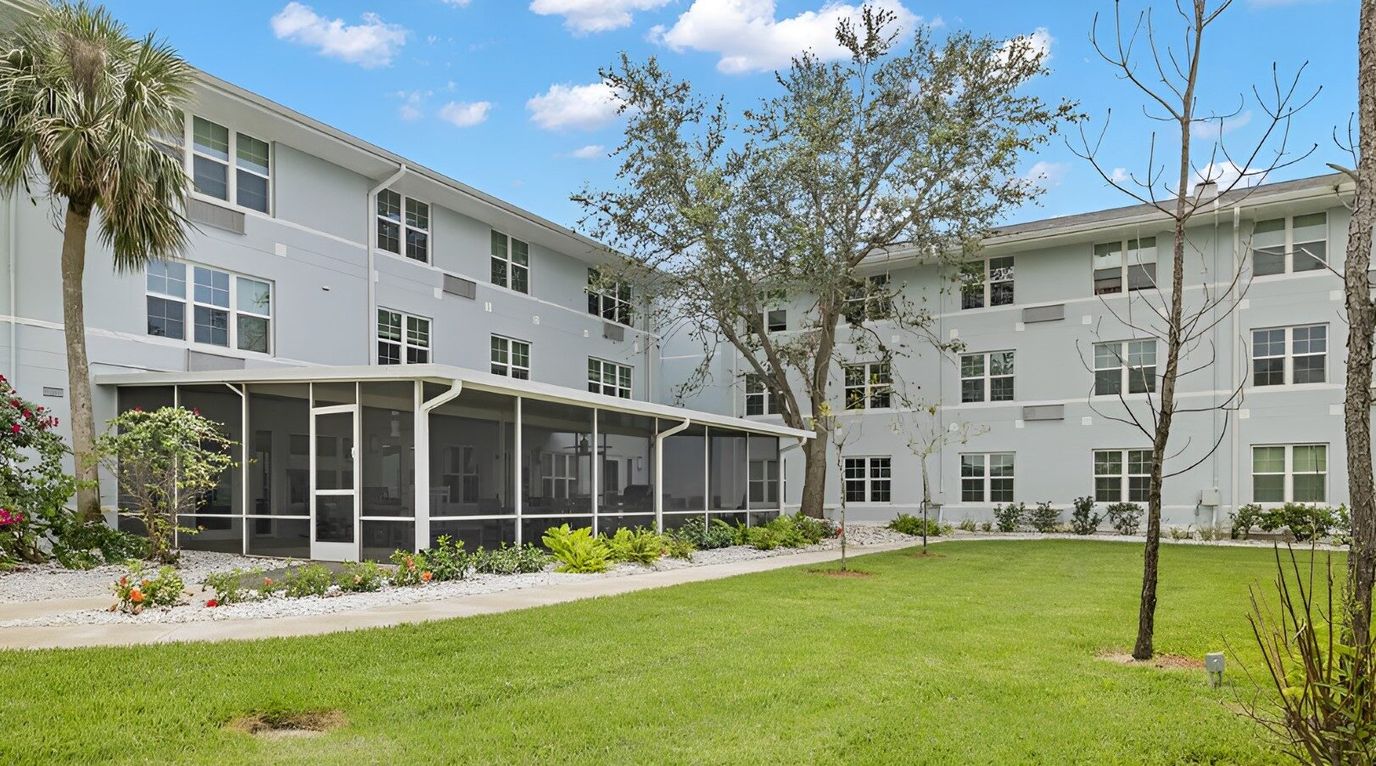 Exterior view of Palm Harbor Apartments' building with garden