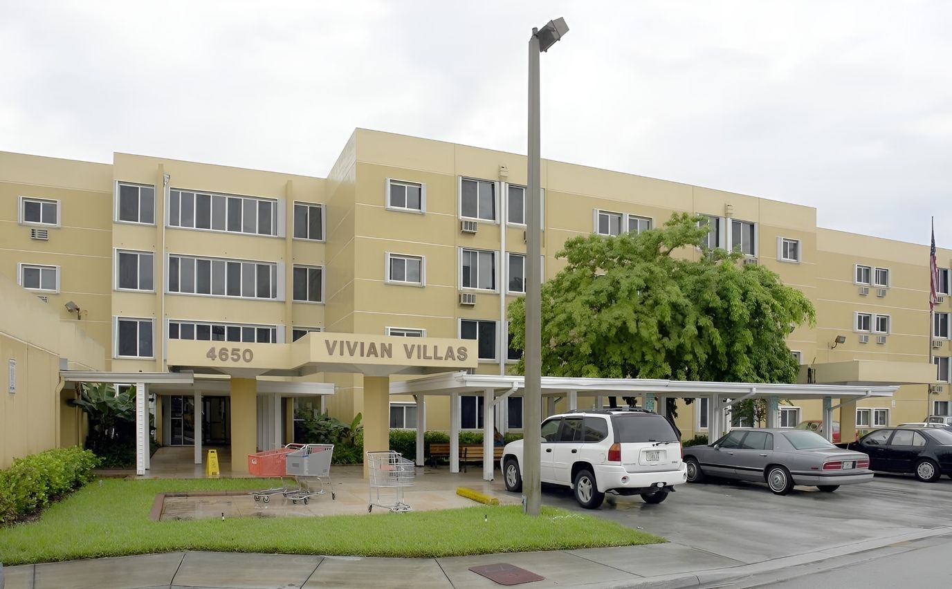 Exterior view of Vivian Villas Apartments with vehicles parked