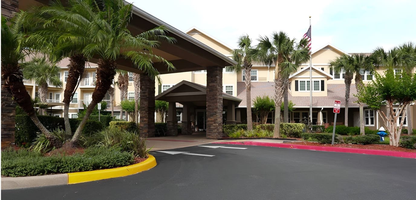 Entrance of a senior living facility surrounded by palm trees