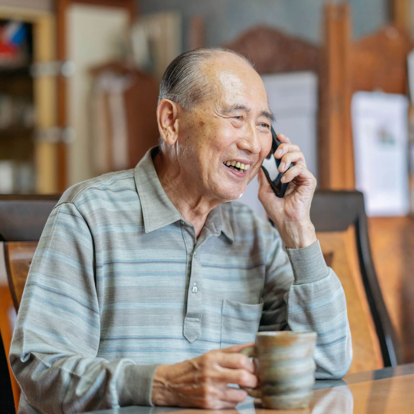 Senior resident enjoying a phone call with coffee