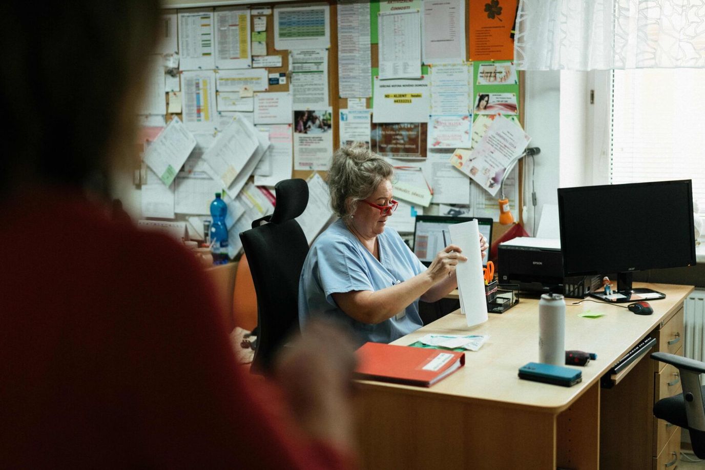 Staff member organizing documents at a desk in an office