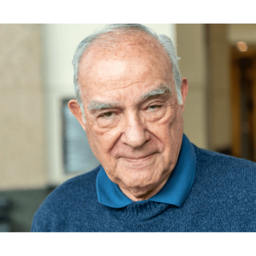 Close-up of an elderly man smiling indoors.