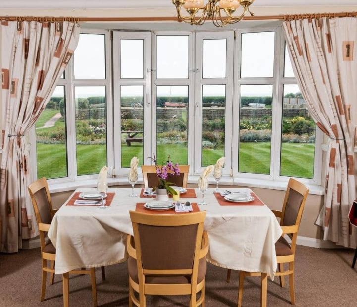 Cedar Court Care Home, memory care in Peterborough, UK — Dining table set by a large bay window