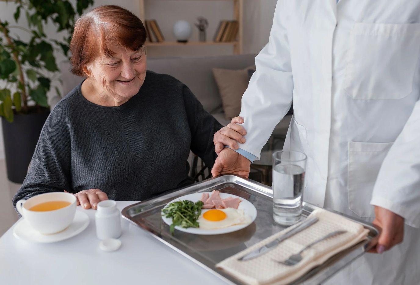 Elderly woman being served a meal by staff.
