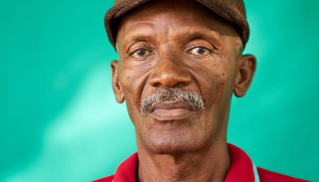 Senior man posing against a green background