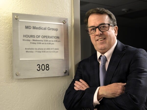 A staff member poses beside an office sign.