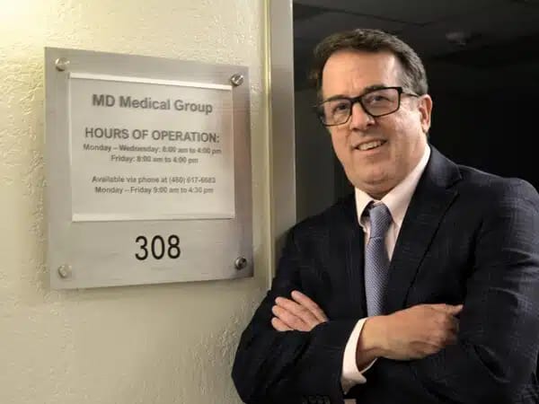 Staff member in front of operation hours sign.