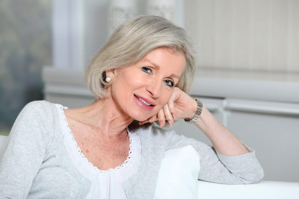 Smiling elderly woman sitting in a cozy interior
