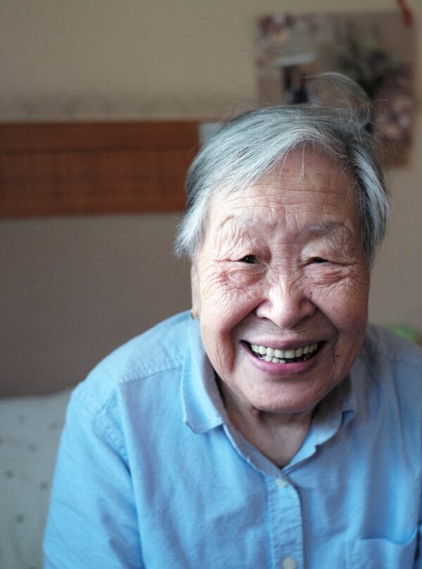 An elderly resident smiling brightly indoors