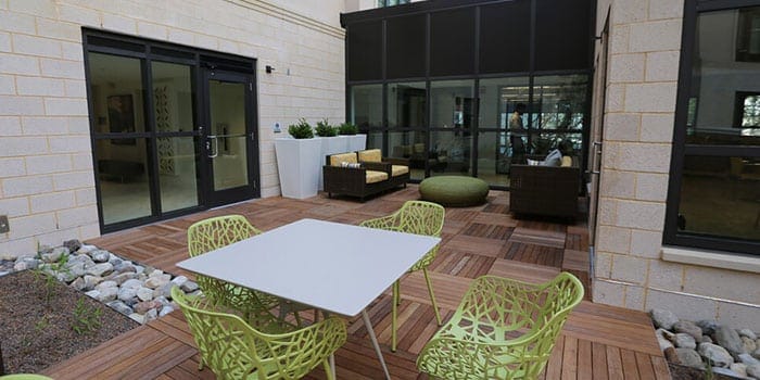 Outdoor seating area with green chairs and a table.