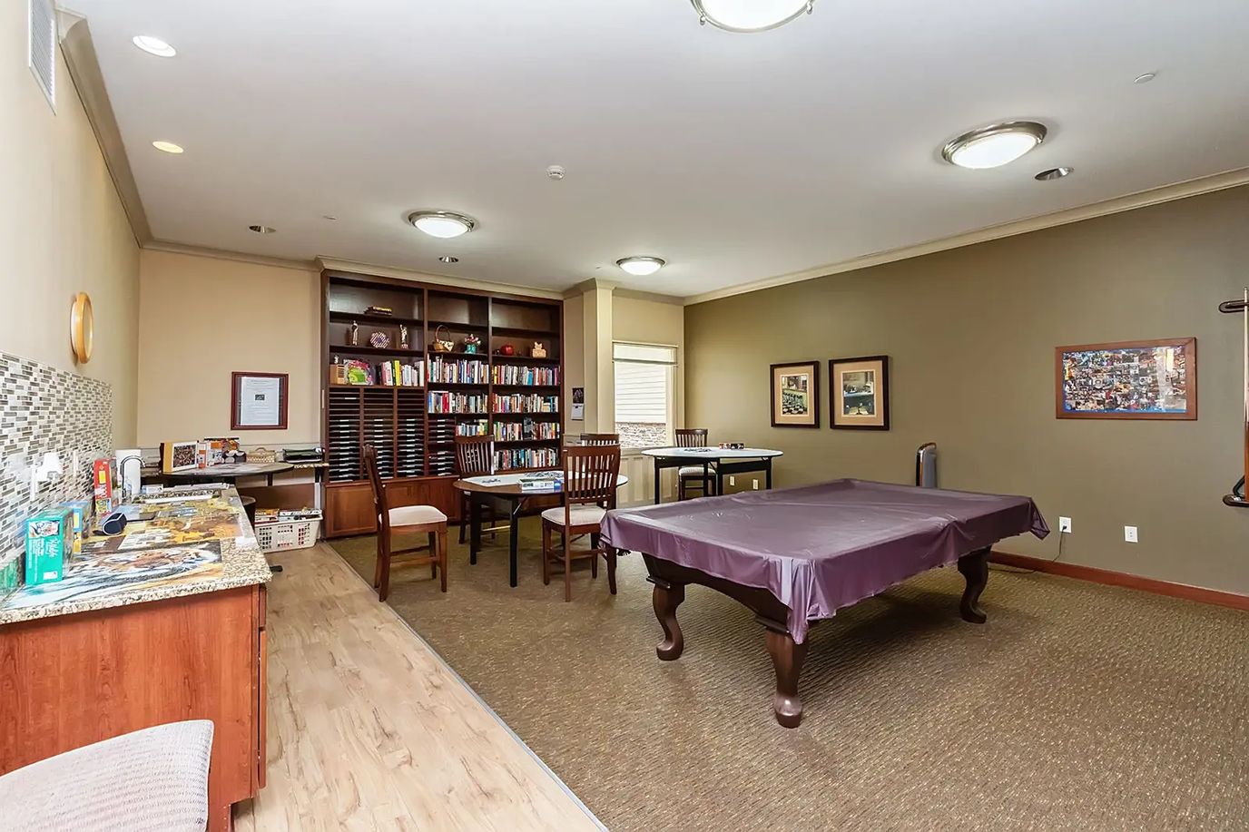 Interior view of the gaming room with a billiard table and bookshelves.