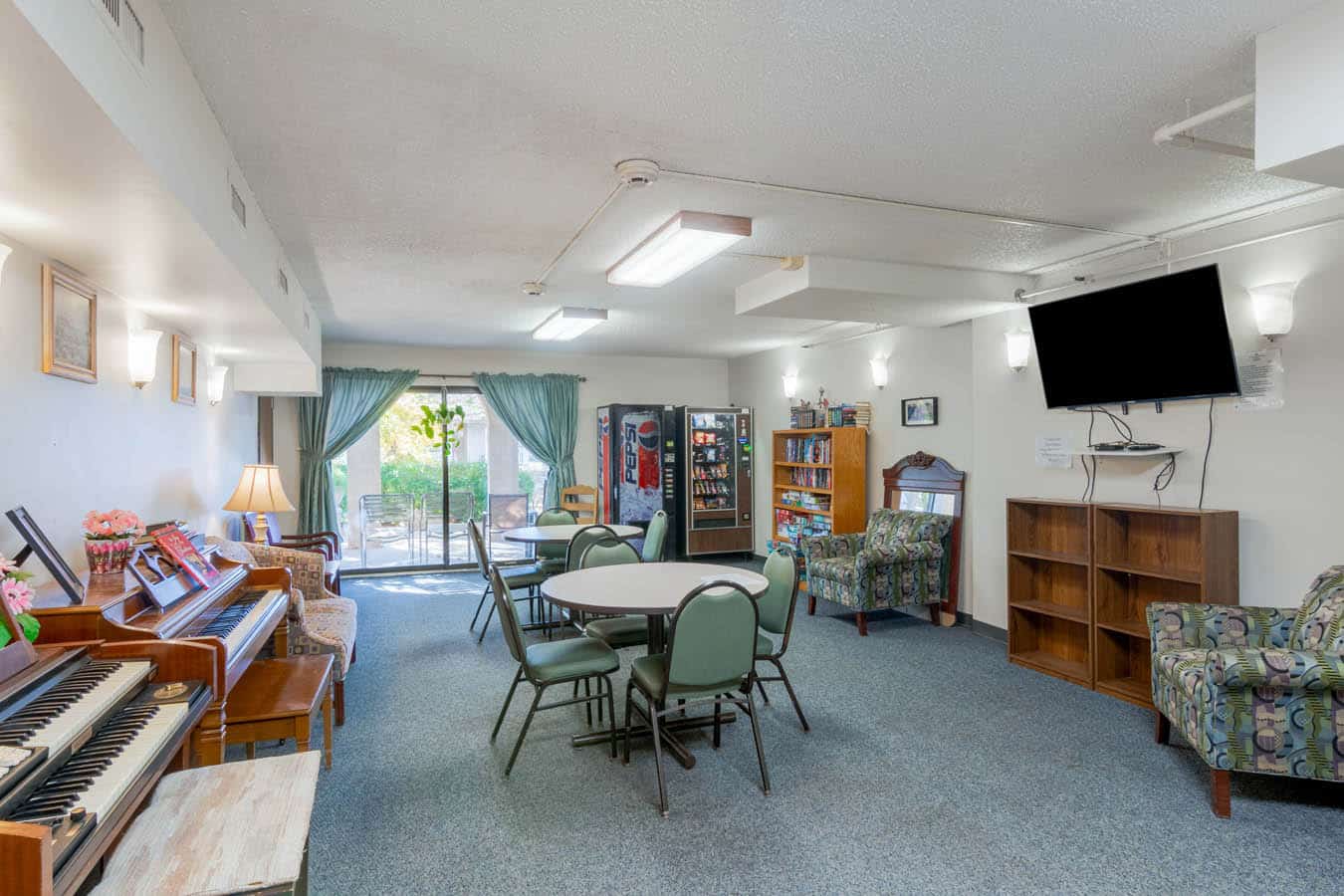 Spacious common area with tables, chairs, and a vending machine