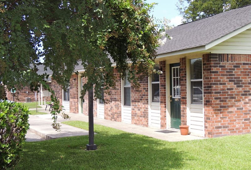 Exterior of a brick building with greenery and a porch