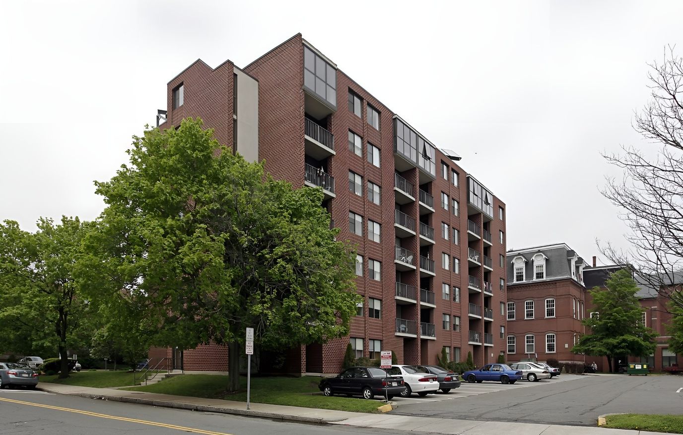 Exterior view of a senior living facility with trees and cars