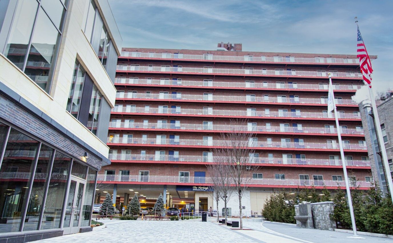 Exterior view of The Heritage Apartments with flag and trees