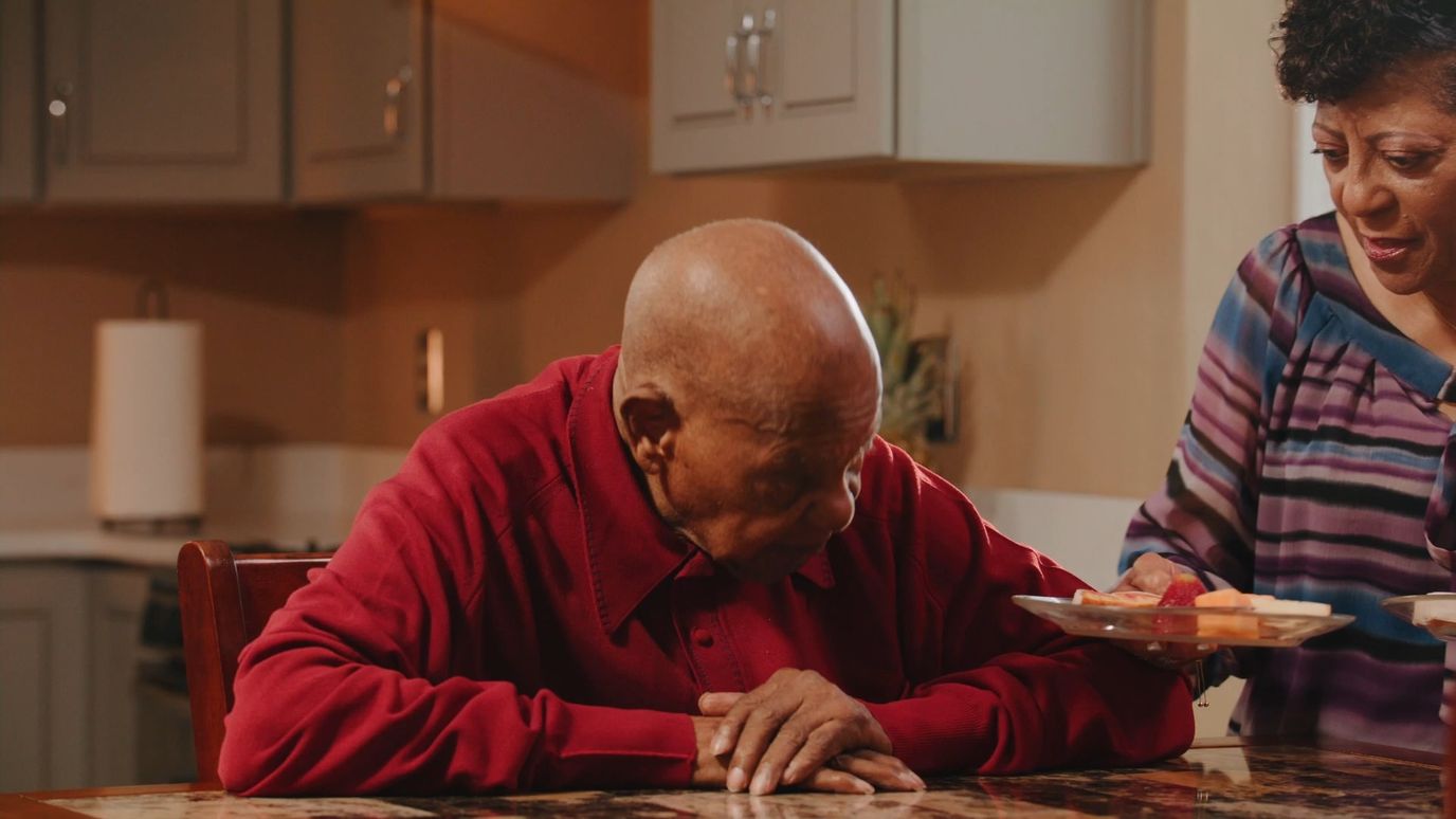 Resident enjoying a meal with staff assistance