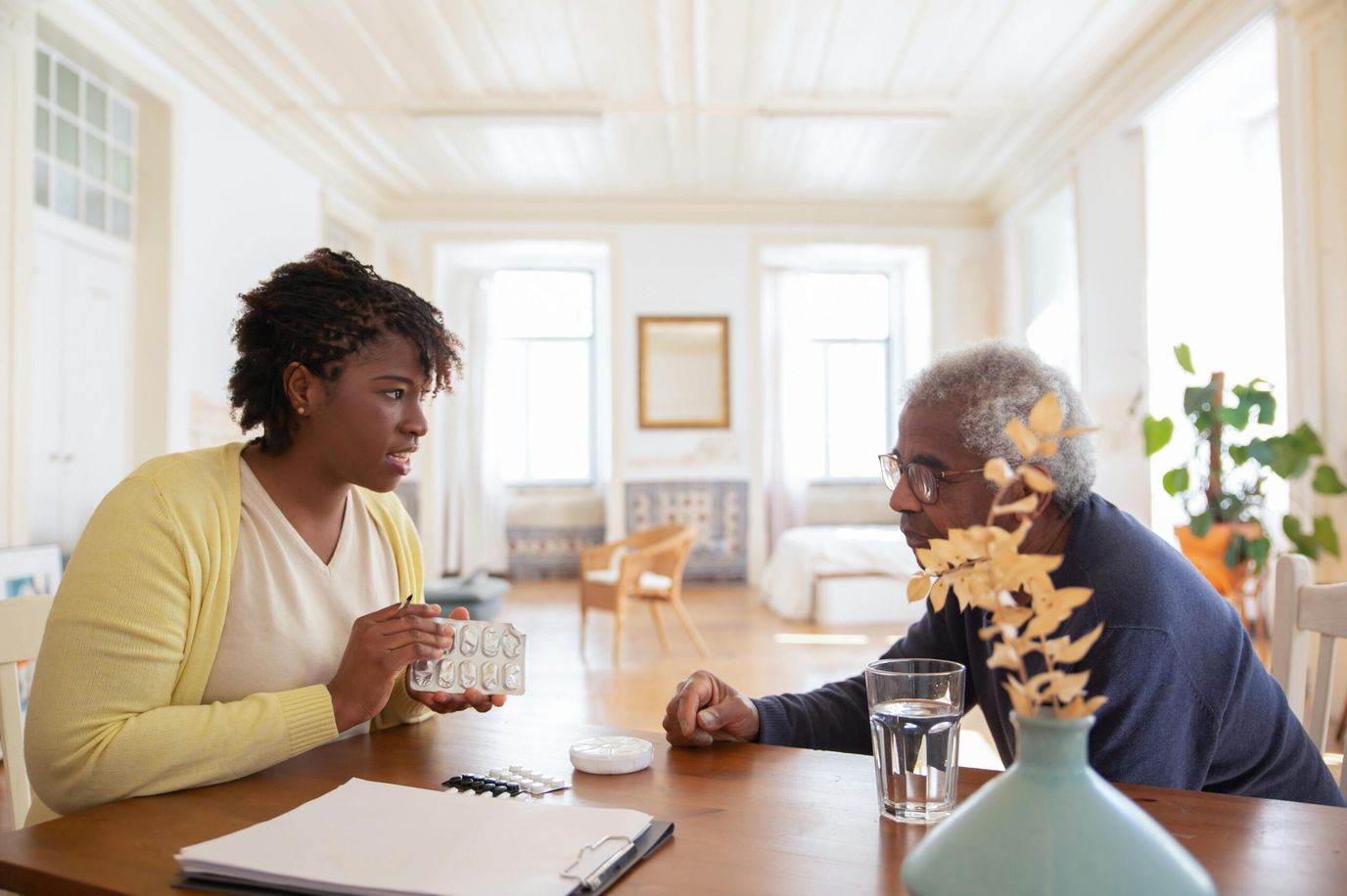 Caregiver discussing medication with a resident at a table