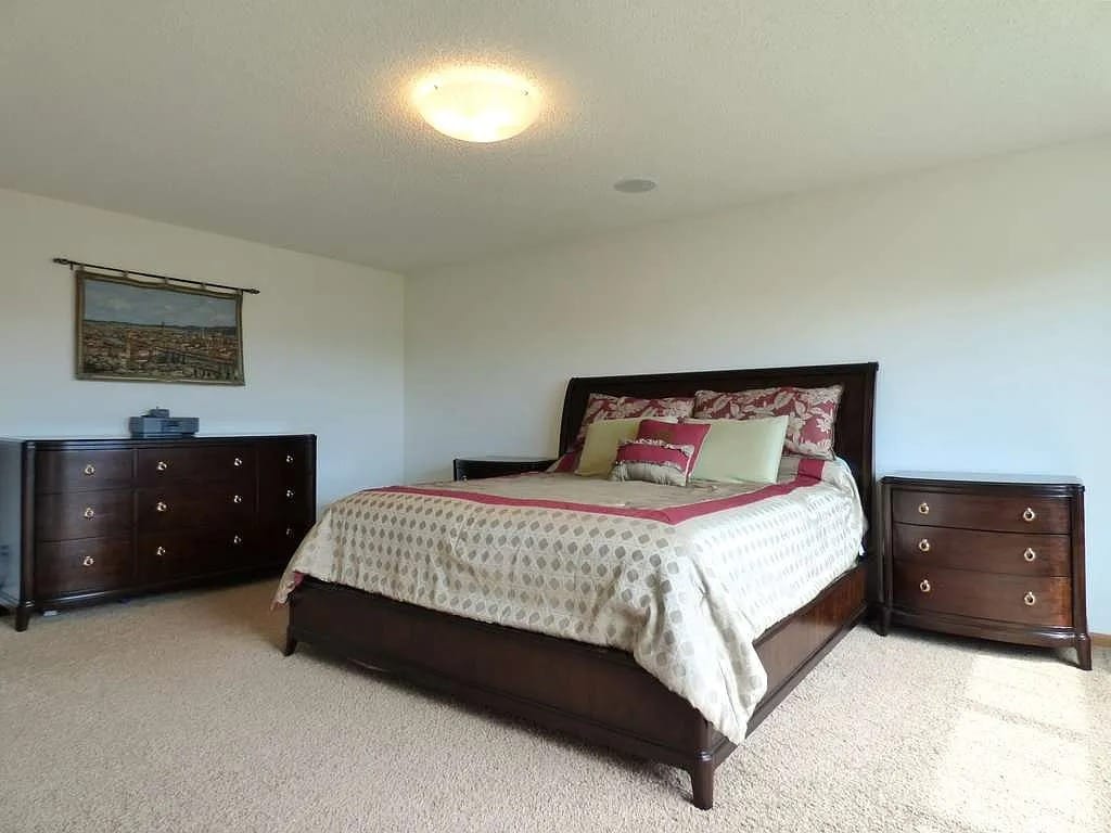 Spacious bedroom with wooden furniture and carpet