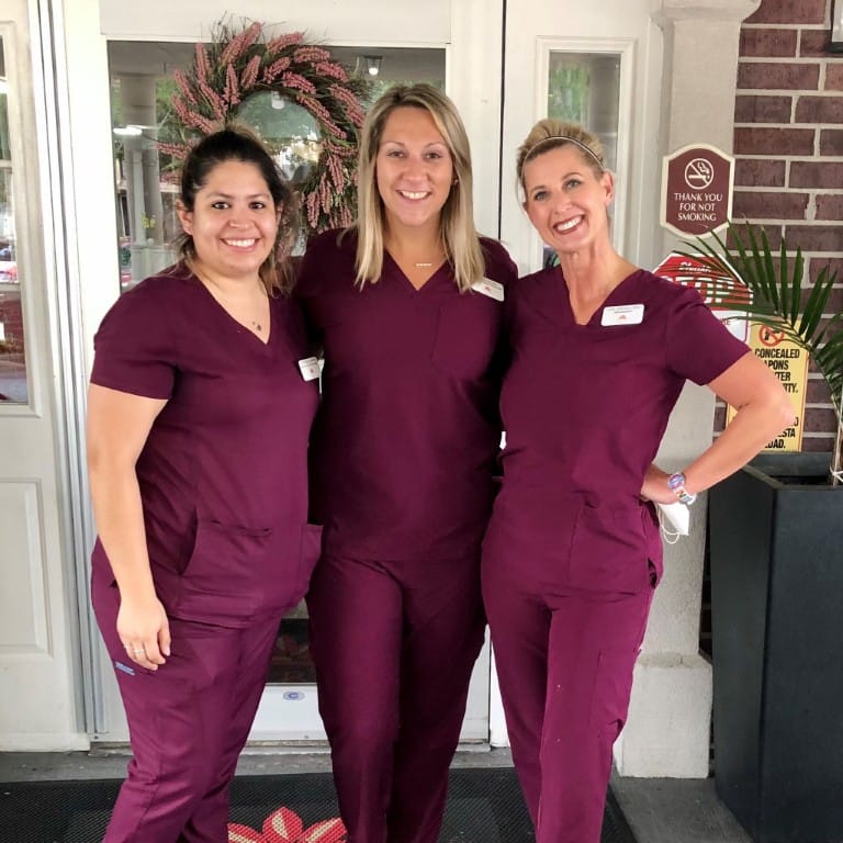 Three staff members smiling at the entrance