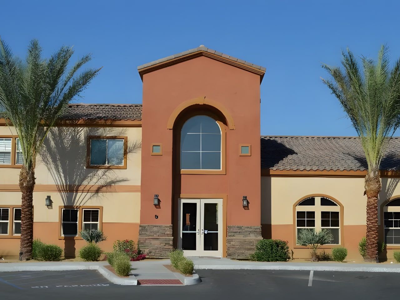 Exterior view of a senior living facility with palm trees