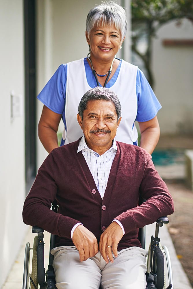 A caregiver with a resident in a wheelchair outside
