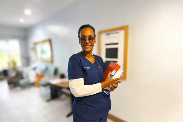 Arabella Health & Wellness of Phenix City, Nursing Home in Phenix City, AL — Staff member holding supplies in a senior living facility