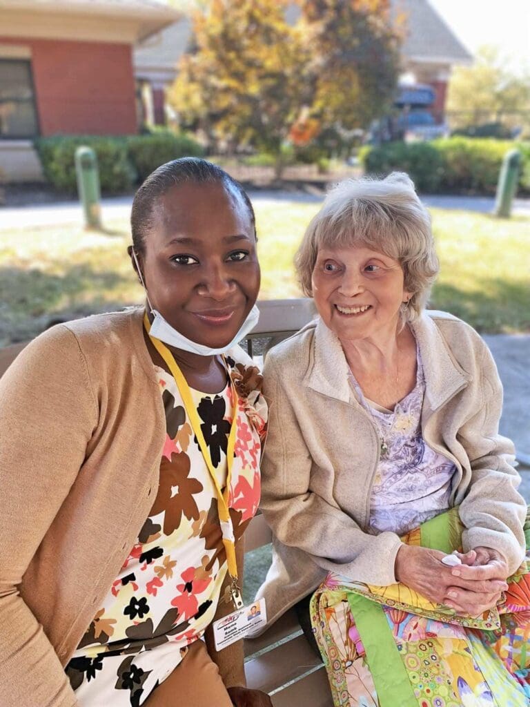 Resident and staff member smiling outdoors