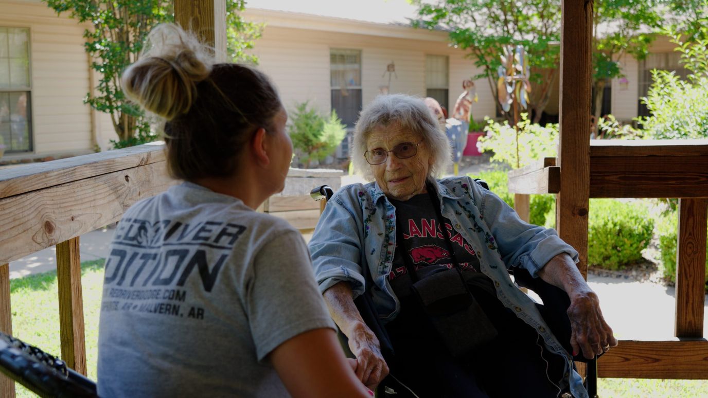 A resident and staff member engaged in conversation outdoors