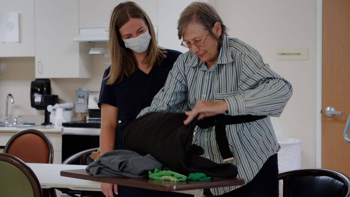 Staff assisting a resident with clothing in a care facility