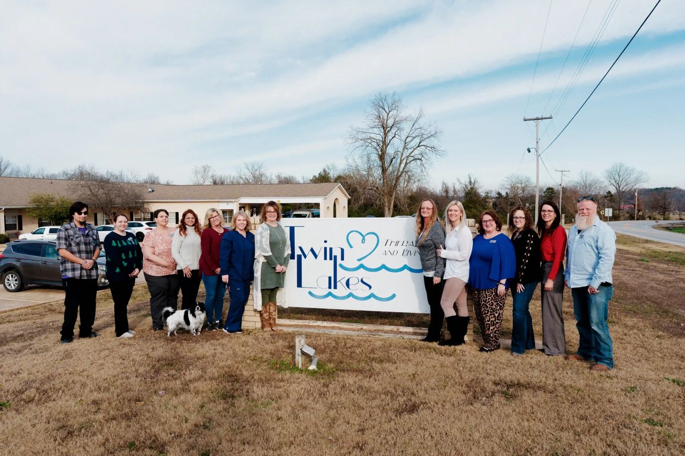 Staff and residents posing in front of the facility sign