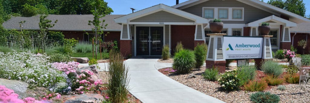 Front entrance of a senior living facility surrounded by gardens