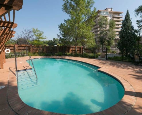 A pool area with greenery and a building in the background