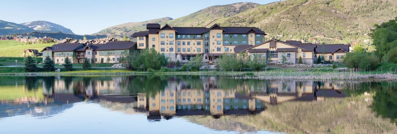 Exterior view of a senior living facility by a lake